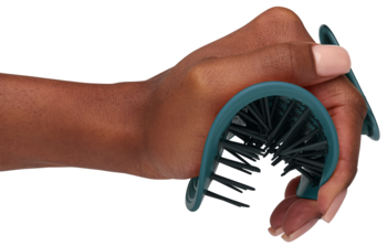 Zbliżenie na rękę trzymającą elastyczną szczotkę MANTA Curls Soft Teal do delikatnego rozczesywania.