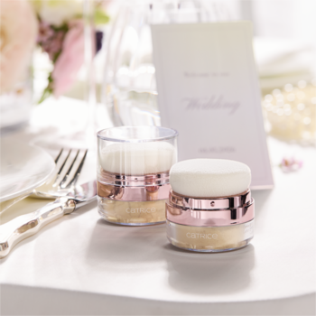 Dwa rozświetlacze Catrice BRIDES & BESTIES Champagne Showers z pędzelkiem, na tle ślubnym.