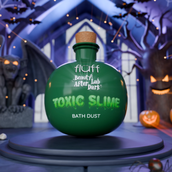 Fluff Beauty Lab Toxic Slime Bath Dust w zielonej butelce z korkiem, na tle spooky zamku Halloween.
