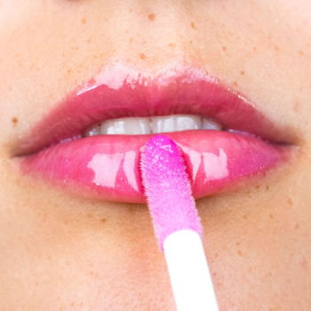 Serum Lip Wonder: zbliżenie na lśniące, różowe usta z aplikatorem XL nakładającym błyszczyk, podkreślającym pełność.