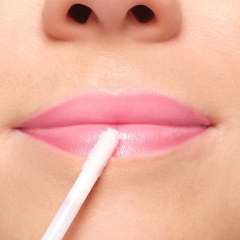 Zbliżenie na usta z błyszczykiem ARTDECO Hot Chili Lip Booster; biały aplikator nakłada produkt na dolną wargę.