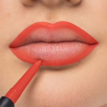 Usta z pomarańczową konturówką Artdeco Mineral Lip Styler, nakładaną na dolną wargę, dla precyzyjnego konturu.