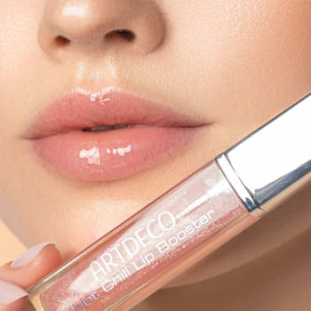 Zbliżenie: błyszczyk ARTDECO Hot Chili Lip Booster w dłoni, prezentuje pełne i błyszczące usta modelki.