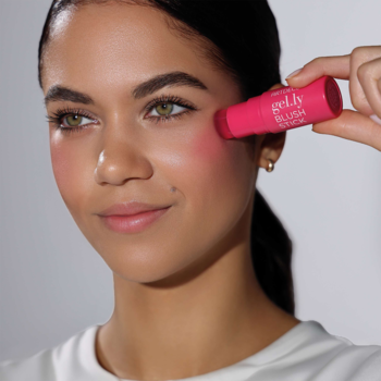 Kobieta nakładająca różowy Artdeco Gel.ly Blush Stick na policzek, nadający naturalny różany rumieniec. Widok z bliska.