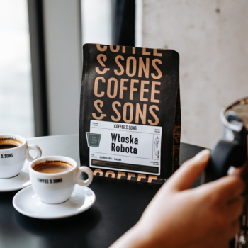 Czarne opakowanie kawy Coffee & Sons Włoska Robota 200g, świeżo palona ziarnista, obok filiżanek espresso.