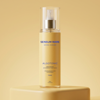 SENSUM MARE ALGOTONIC, rozświetlający tonik 150ml w żółtej butelce z atomizerem na beżowym postumencie.