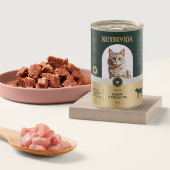 Puszka zielonej karmy Nutrivida z cielęciną dla kota, obok miska pasztetu i drewniana łyżka z surowym mięsem.