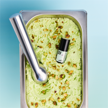 Lakier essence UV GEL 215 Pistachio Gelato zanurzony w pistacjowych lodach z gałkownicą, widok z góry.