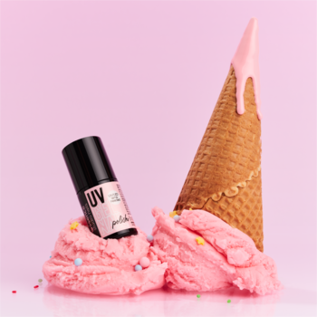 Czarna butelka lakieru essence UV GEL NAIL 217 Blush In A Cone na różowych lodach z rożkiem i posypką.