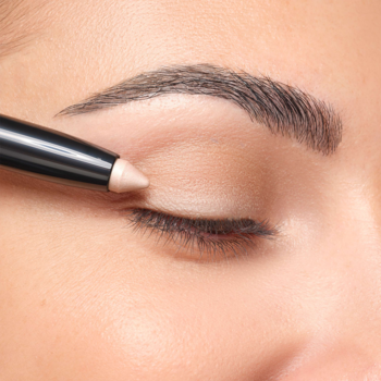 Zbliżenie na zamknięte oko, aplikacja kremowego cienia Artdeco High Performance Eyeshadow Stylo Seashell na powiekę.