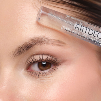 Zbliżenie na kobiece oko i brew, z aplikatorem przezroczystego żelu ARTDECO Clear Lash&Brow Gel.