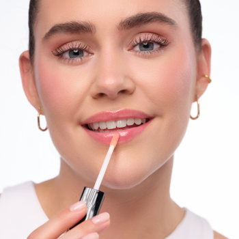 Zbliżenie na kobietę aplikującą nawilżający błyszczyk Artdeco Hydra Lip Booster Translucent Mauve na lśniące usta.