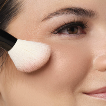 Róż do policzków Artdeco Beige Rose Blush nakładany pędzlem na kość policzkową modelki.