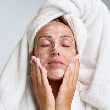 Kobieta w ręczniku aplikuje nawilżającą piankę do demakijażu Swederm Face Cleanser na twarz.