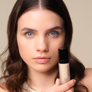 Kobieta trzyma beżowy podkład Artdeco Perfect Teint Soft Vanilla, lekko matujący, widok z przodu.