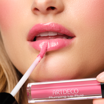 Kobieta aplikuje różowy błyszczyk Artdeco Plumping Lip Fluid w odcieniu Juicy Berry na pełne, lśniące usta.