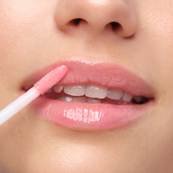 Zbliżenie na aplikację różowego błyszczyka Artdeco Plumping Lip Fluid na usta, dla efektu wet look.