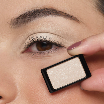 Artdeco Glam Natural Skin brokatowy cień do powiek w jasnym, szampańskim odcieniu, trzymany przy oku z makijażem.