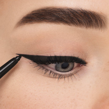 Zbliżenie: aplikacja czarnego eyelinera Mineral Eye Styler na powiekę, tworząca precyzyjną kreskę kredki.