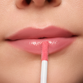 Zbliżenie na usta aplikujące Plumping Lip Fluid. Różowy błyszczyk nadaje pełny, lśniący i nawilżający efekt.