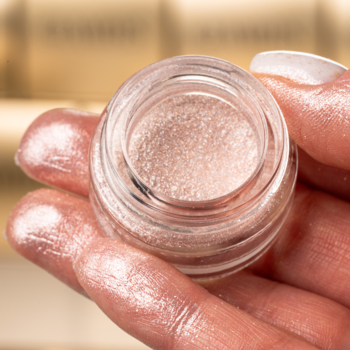 Glamtes Pearl Luster pigment: zbliżenie na szklany słoiczek z perłowym, lśniącym cieniem trzymany w dłoni.