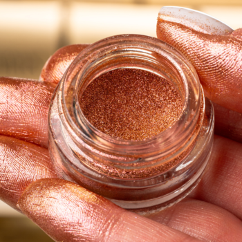 Zbliżenie na GLAMTES Love Sunrise 10, błyszczący różowo-złoty pigment w słoiczku, na palcach dłoni.