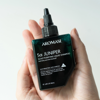 Aromase 5α Juniper Scalp Purifying Liquid Shampoo, ciemnozielona butelka z kroplomierzem, w dłoni.