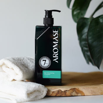 AROMASE Hair Volumizing Shampoo, czarna butelka z pompką, z zieloną etykietą, na drewnianej desce i białym ręczniku.