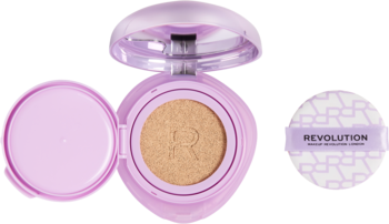 Otwarty liliowy podkład w kompakcie Revolution Superdewy Cushion Foundation Light Neutral Warm ze złotym odcieniem i puszystą gąbeczką obok.