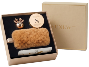 Otwarty beżowy zestaw Iconic Goddess Sunew: futrzana kosmetyczka, balsam, odświeżacz renifer, w tle zamknięte pudełko.