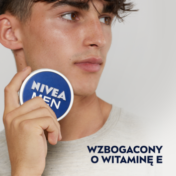 Mężczyzna trzyma granatowy krem NIVEA MEN Creme z witaminą E. Widok z bliska na puszkę i część twarzy.