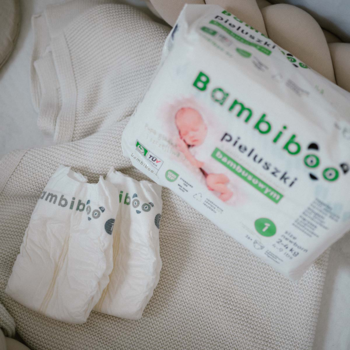 Bambiboo pieluszki jednorazowe z włóknem bambusowym, opakowanie rozmiar 1 i dwie pieluszki na białym kocu.