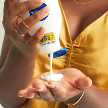 Nivea Q10 + Witamina C ujędrniający balsam do ciała, wyciskany z białej butelki z niebieską nakrętką do dłoni.