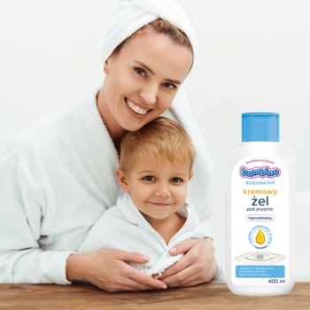 Bambino Rodzina kremowy żel pod prysznic 400ml, biała butelka z niebieską nakrętką, obok uśmiechnięta matka z dzieckiem.