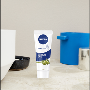 Krem do rąk NIVEA Moisture Care z oliwą oliwek w białej tubce, widok z przodu na jasnym blacie.