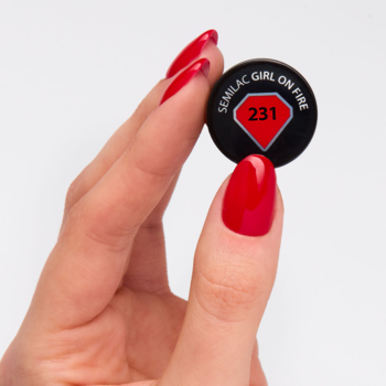 Dłoń z pomalowanymi na czerwono paznokciami trzyma czarny tester lakieru Semilac 231 Girl on Fire, klasyczna czerwień.