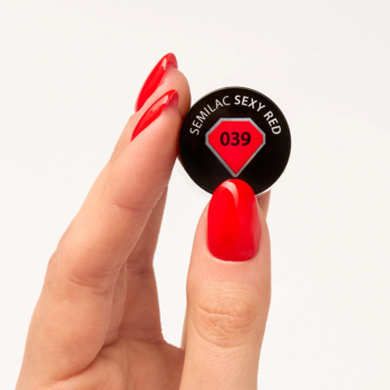 Nakrętka lakieru Semilac 039 Sexy Red w intensywnym, ciepłym odcieniu czerwieni, trzymana w dłoni z pasującymi paznokciami.