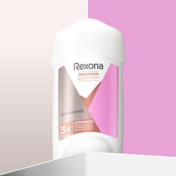 Kremowy antyperspirant Rexona Maximum Protection Confidence, biały stick z różową etykietą, różowo-białe tło.