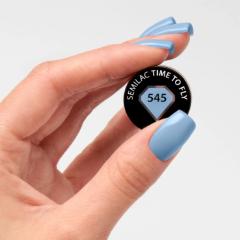 Kobieta trzyma czarny wzornik lakieru hybrydowego Semilac 545 Time to Fly. Paznokcie w kolorze chłodnego błękitu.