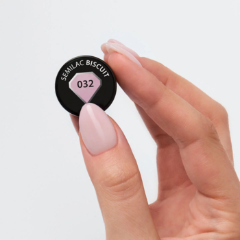 Lakier hybrydowy Semilac 032 Biscuit: nakrętka w dłoni z paznokciami pomalowanymi na jasny mleczny róż.