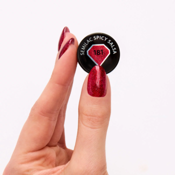 Lakier hybrydowy Semilac 181 Spicy Salsa: dłoń trzyma zakrętkę, paznokcie w brokatowej, karminowej czerwieni.