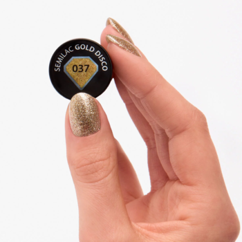 Złoty brokatowy lakier hybrydowy Semilac Gold Disco 037. Zbliżenie dłoni z pomalowanym paznokciem, trzymającej czarny korek.