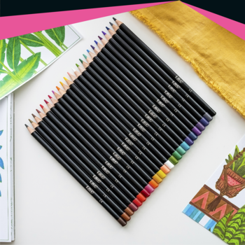 Zestaw czarnych kredek premium z żywymi kolorami, ułożonych wachlarzowo na stole obok rysunków i złotej kosmetyczki.