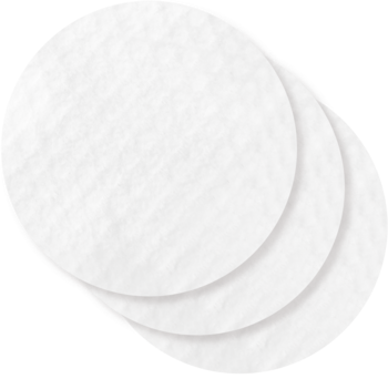 Białe, okrągłe płatki 100% bawełny, nasączone zmywaczem do paznokci, lekko rozłożone w stos na ciemnym tle.