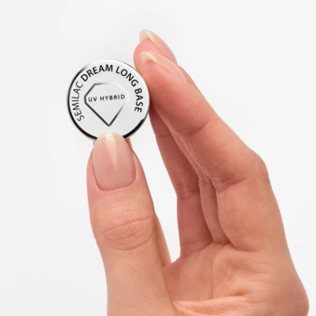Dłoń trzyma okrągłą, białą bazę Semilac Dream Long Base UV Hybrid, dla mocnych i długich paznokci.