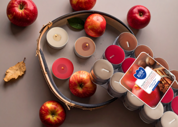 Z góry: świece zapachowe jabłko-cynamon. Tealighty w odcieniach beżu i czerwieni, część w opakowaniu, czerwone jabłka, taca.