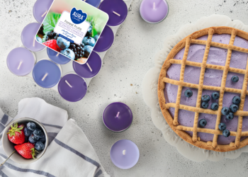 Fioletowe świece zapachowe tealight Owoce Leśne, widok z góry. Obok tarta i świeże truskawki z jagodami.