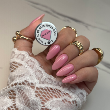 Ręka z długimi różowymi paznokciami i pierścionkami trzyma Semilac BB Base Super Rose, bazę kauczukową.