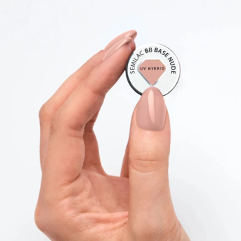 Ręka trzyma okrągły słoiczek Semilac 80 Base Nude UV Hybrid z próbką beżowej bazy kauczukowej.
