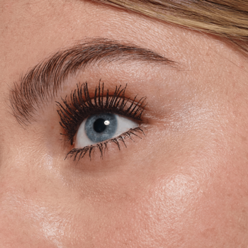 Zbliżenie na oko z rzęsami pokrytymi brązową maskarą Volume Million Lashes Balm Brown, dodającą im objętości.